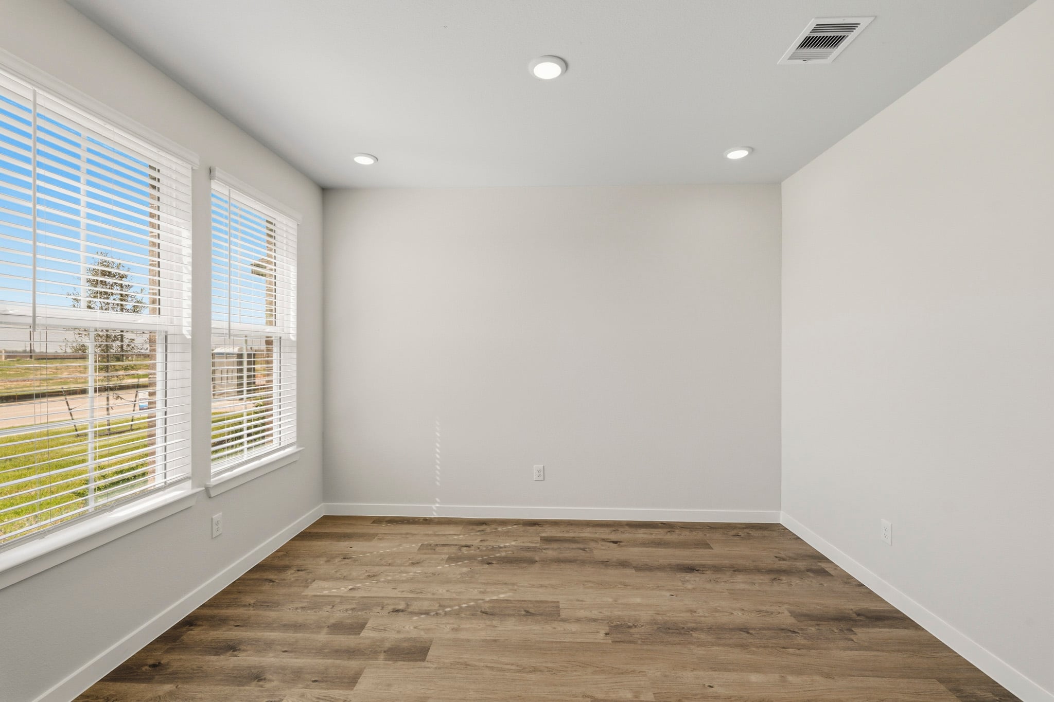 A room with a wood floor and windows.