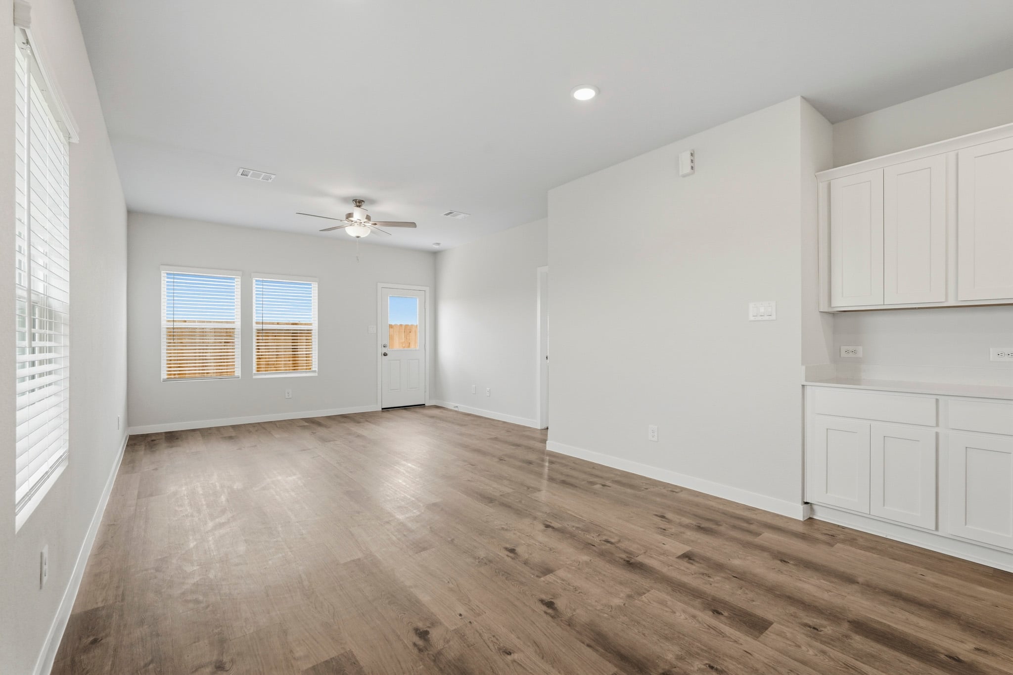A room with white cabinets and a wood floor.