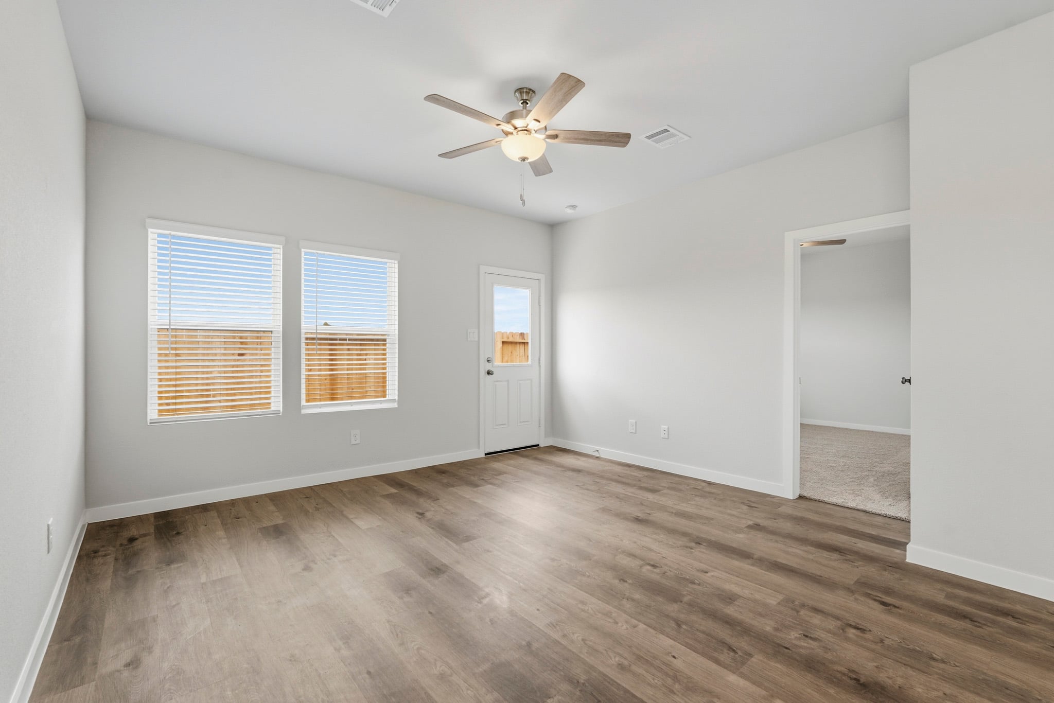 A room with a ceiling fan and a wood floor.