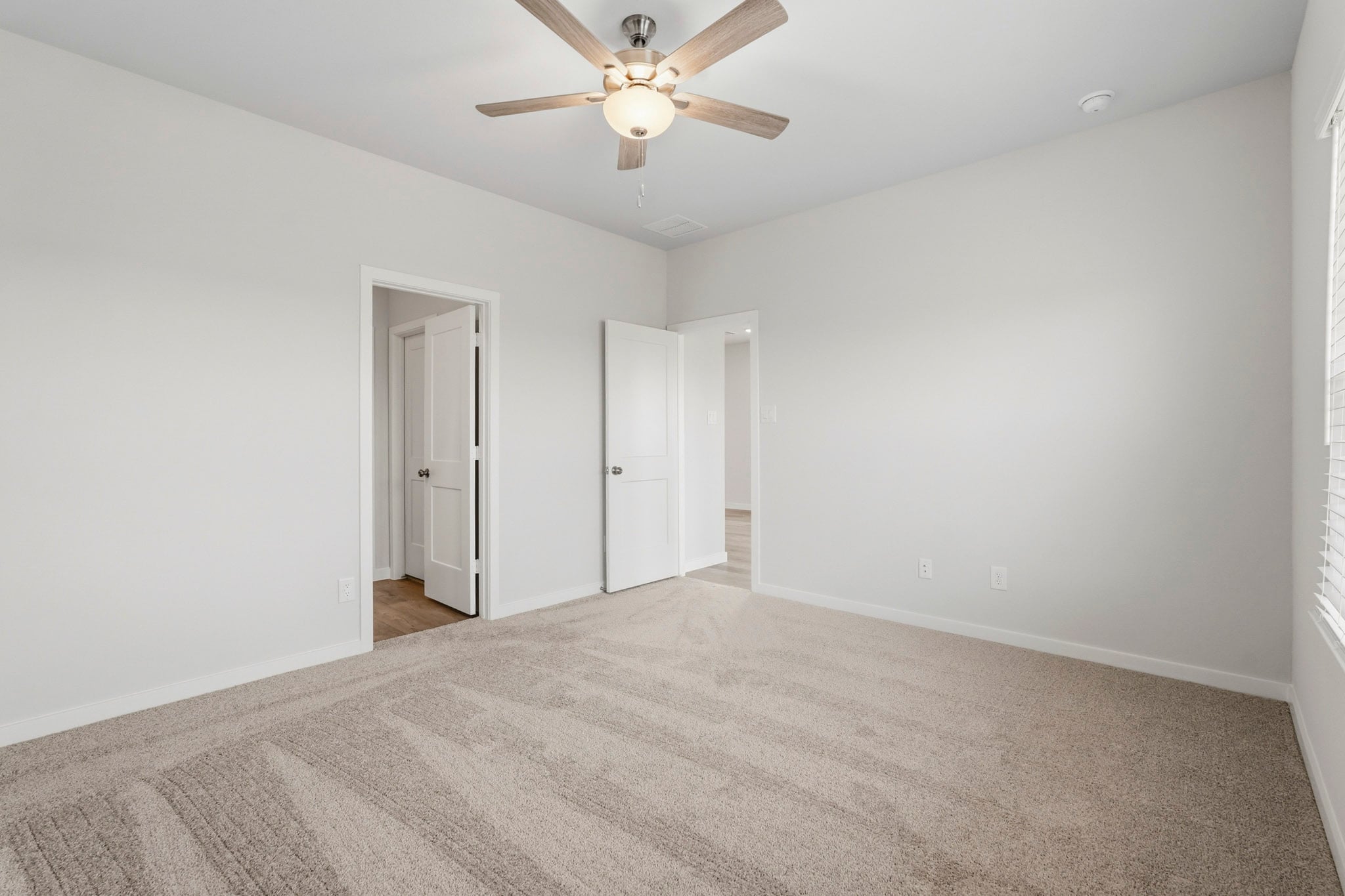 A room with a ceiling fan and a door.