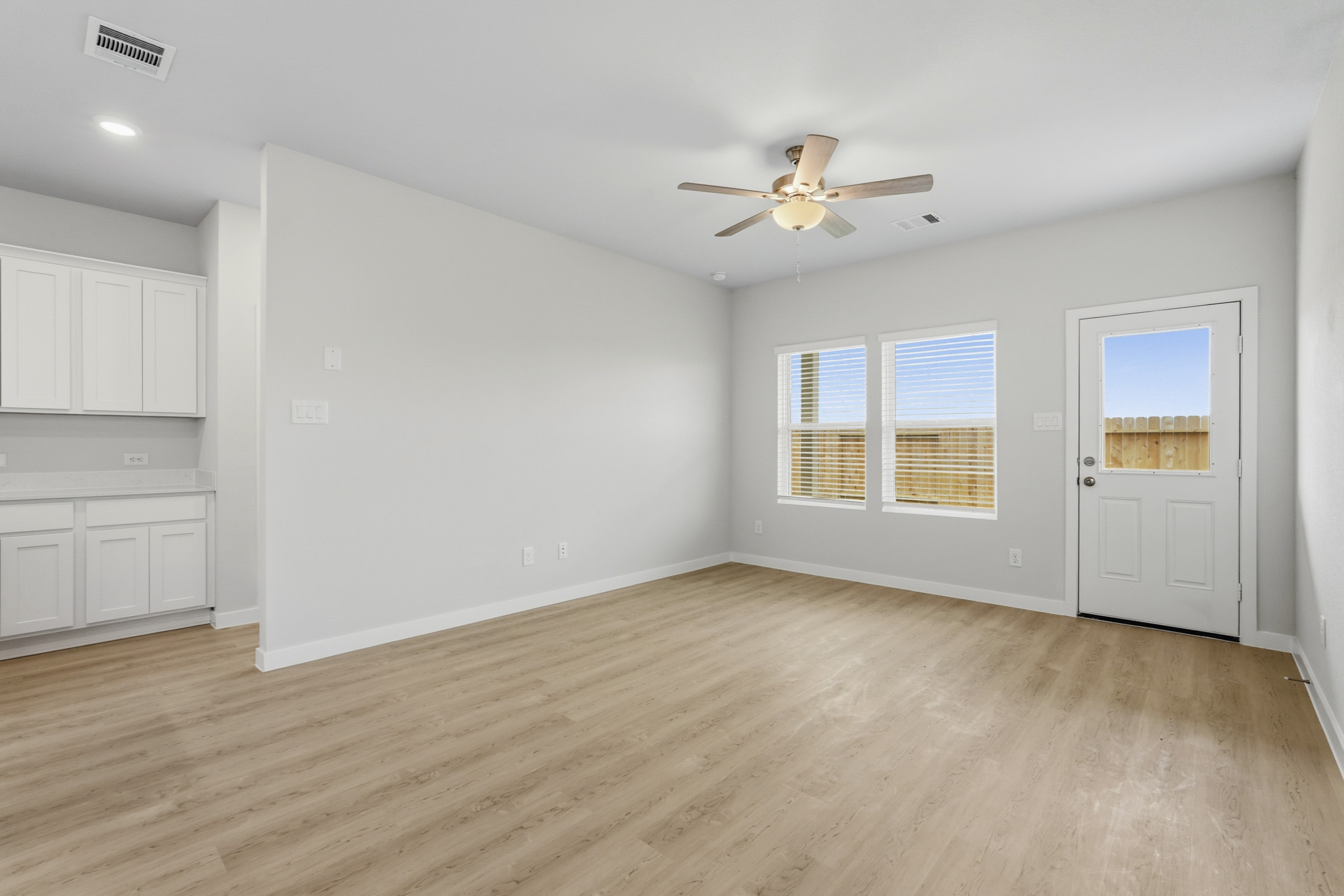 A room with a ceiling fan and a wood floor.