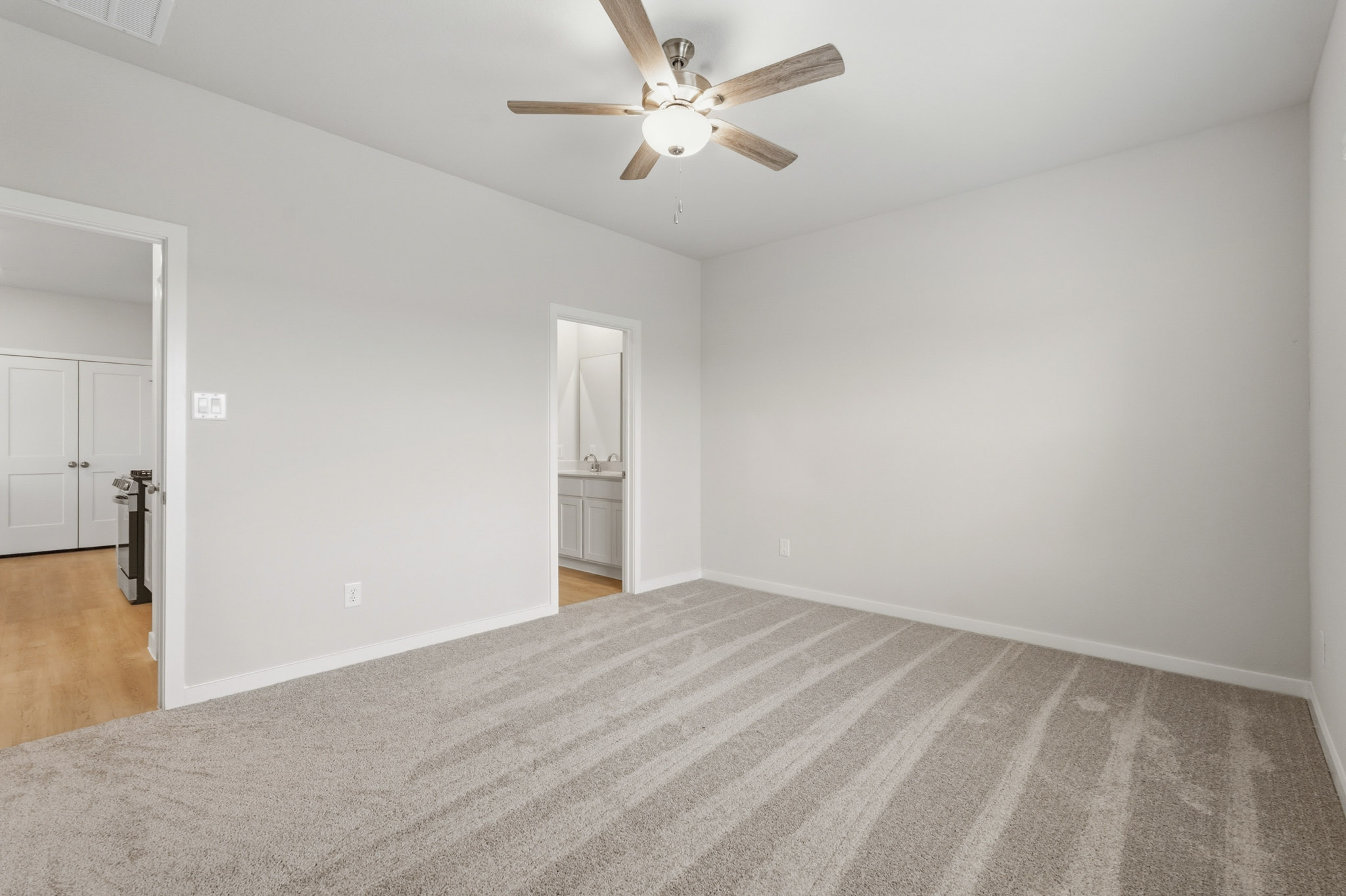A room with a ceiling fan and a carpet.