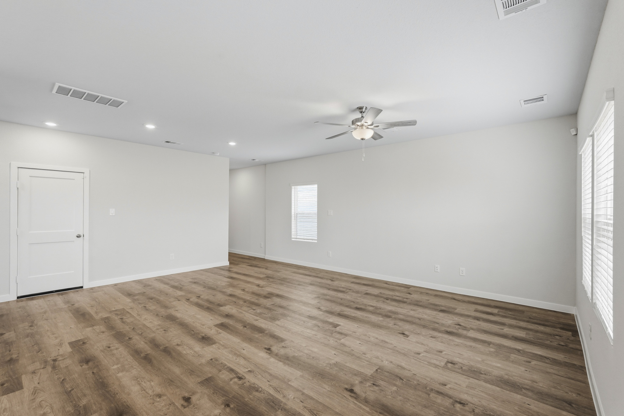 A room with a ceiling fan and wood floor.