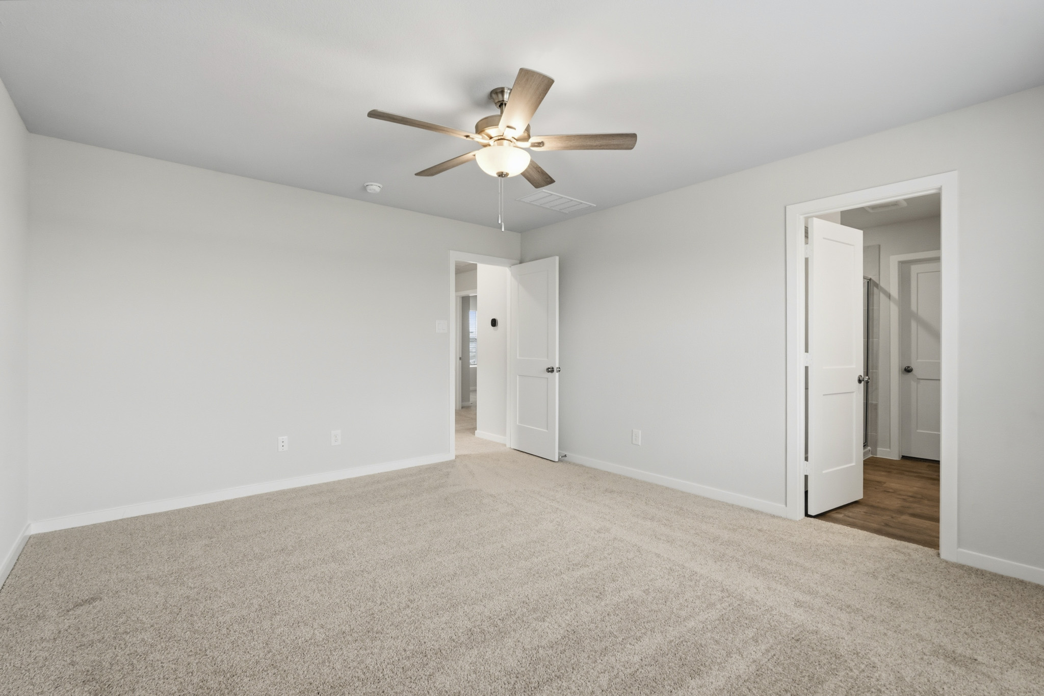 A room with a ceiling fan and white walls.