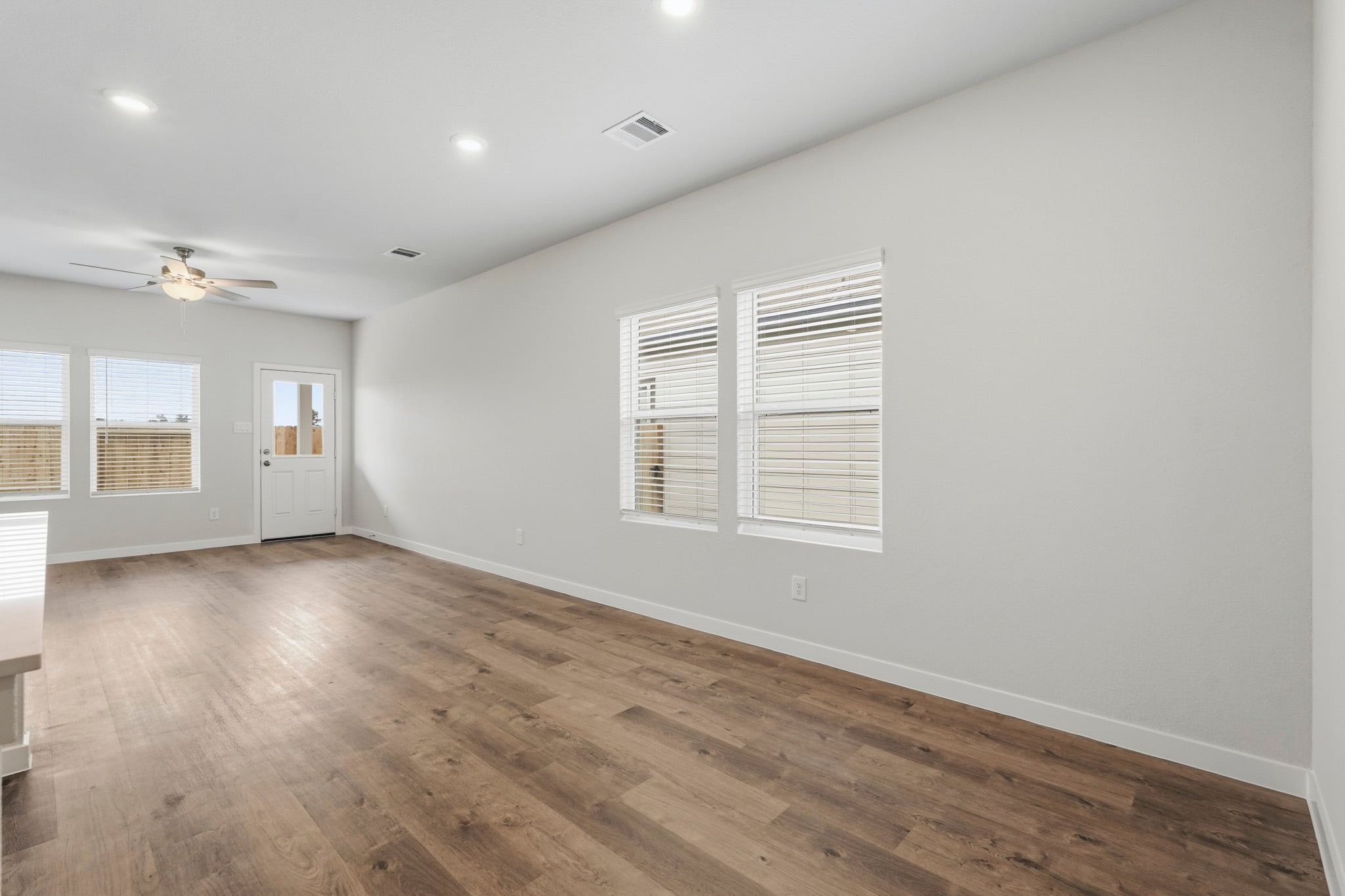 A room with a wood floor and a wood floor with a fan.