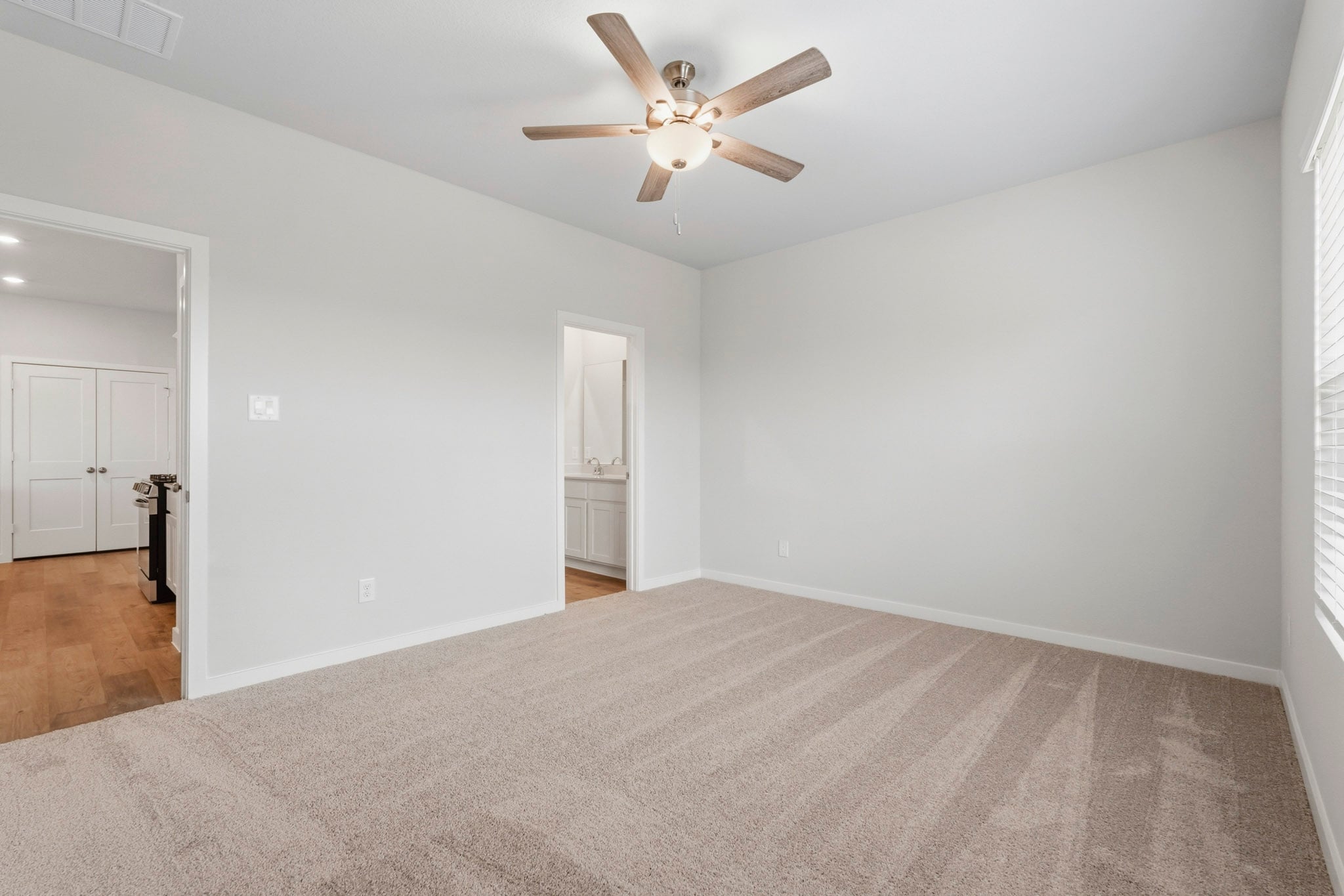 A room with a ceiling fan and a carpet.