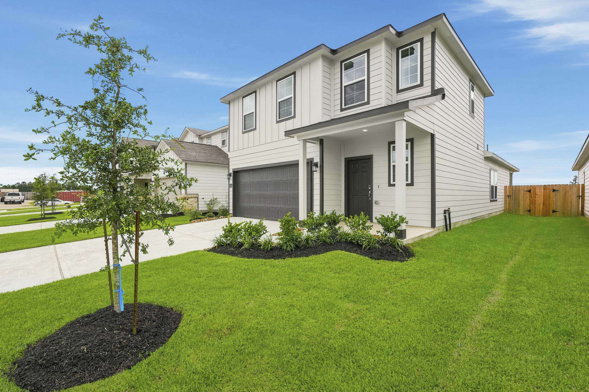 A house with a yard and a tree in front of it.