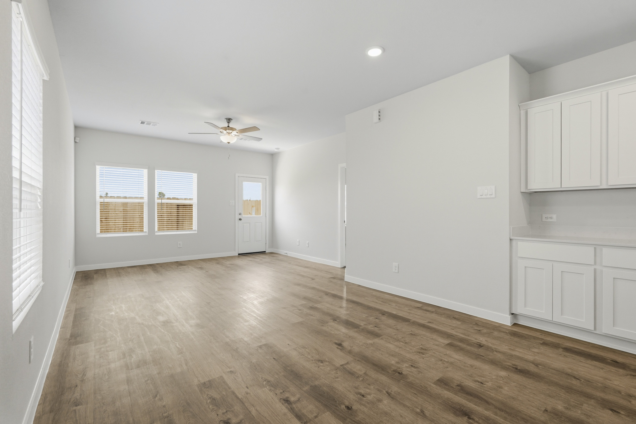 A room with white cabinets and a wood floor.