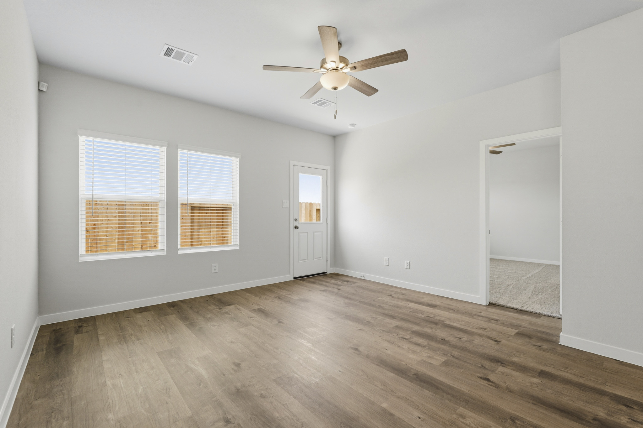 A room with a wood floor and a ceiling fan.