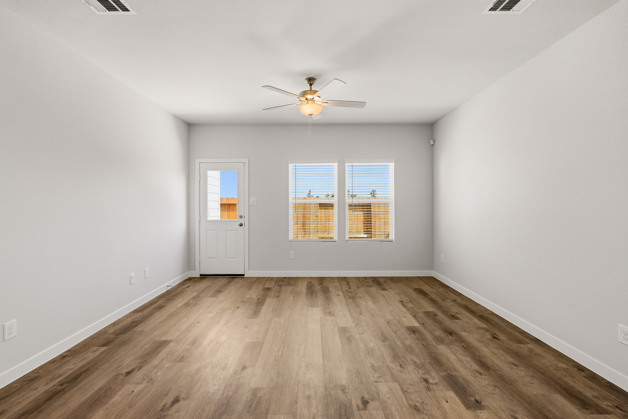 A room with a wood floor and a ceiling fan.