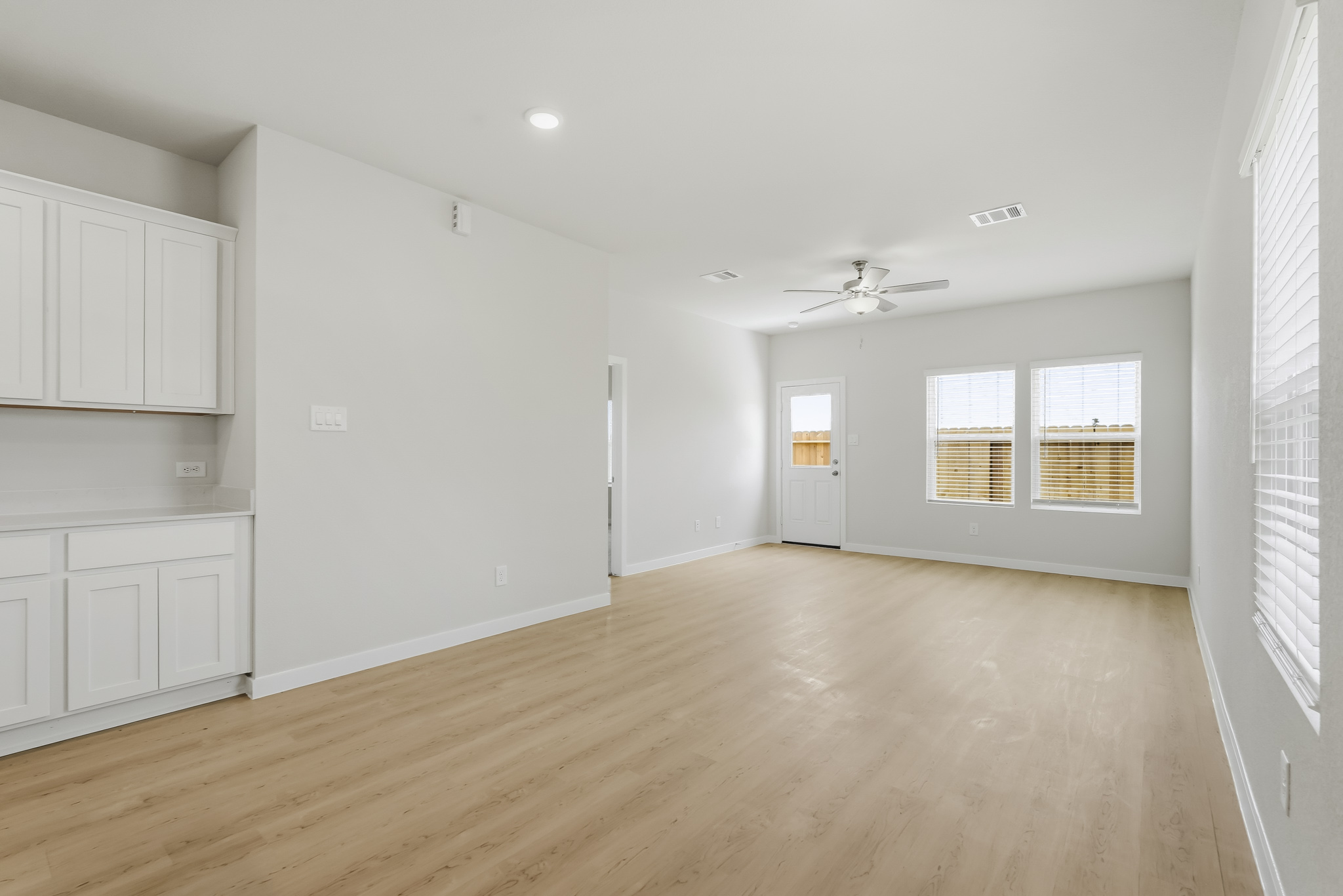 A room with white cabinets and a wood floor.