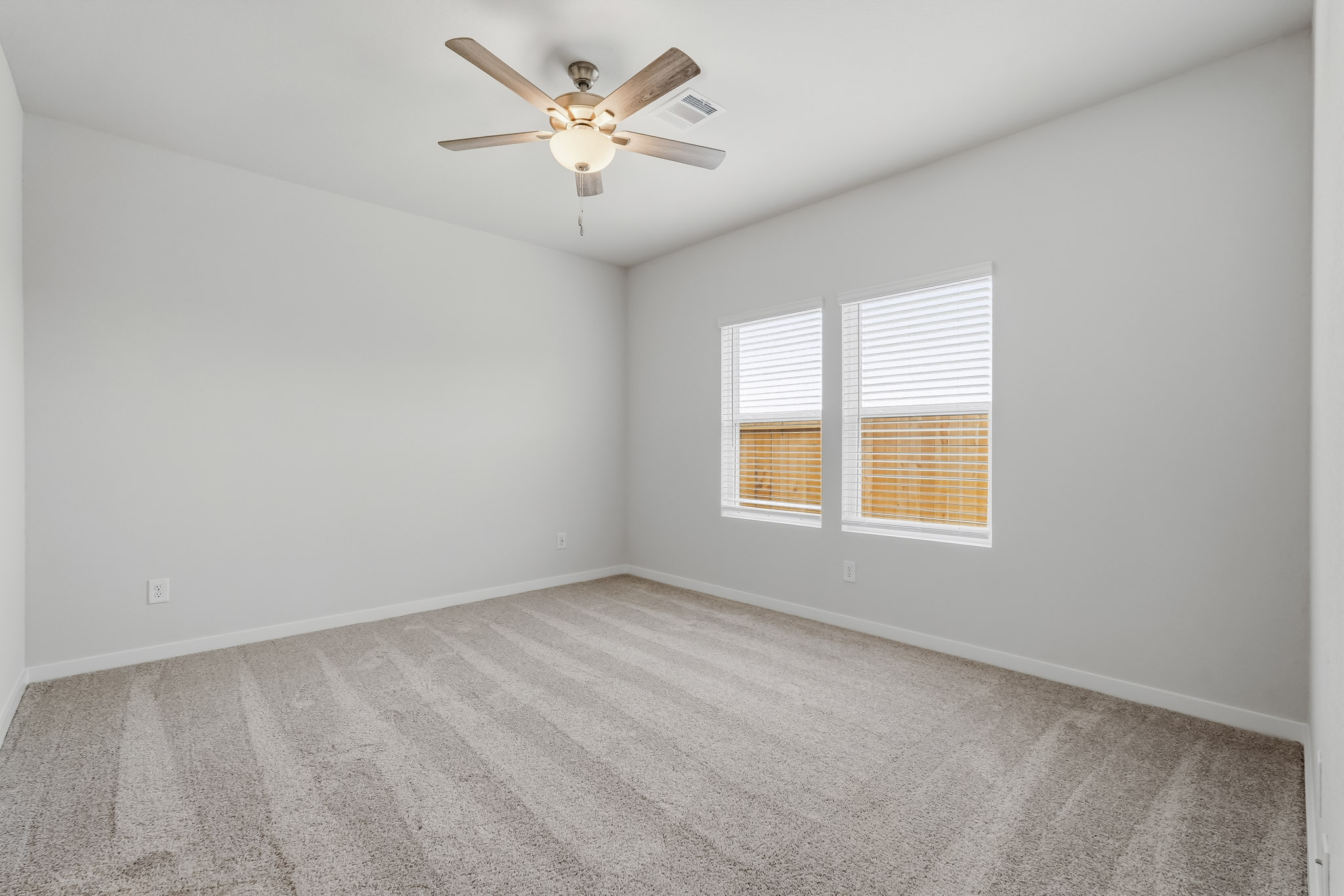 A room with a ceiling fan and a carpet.