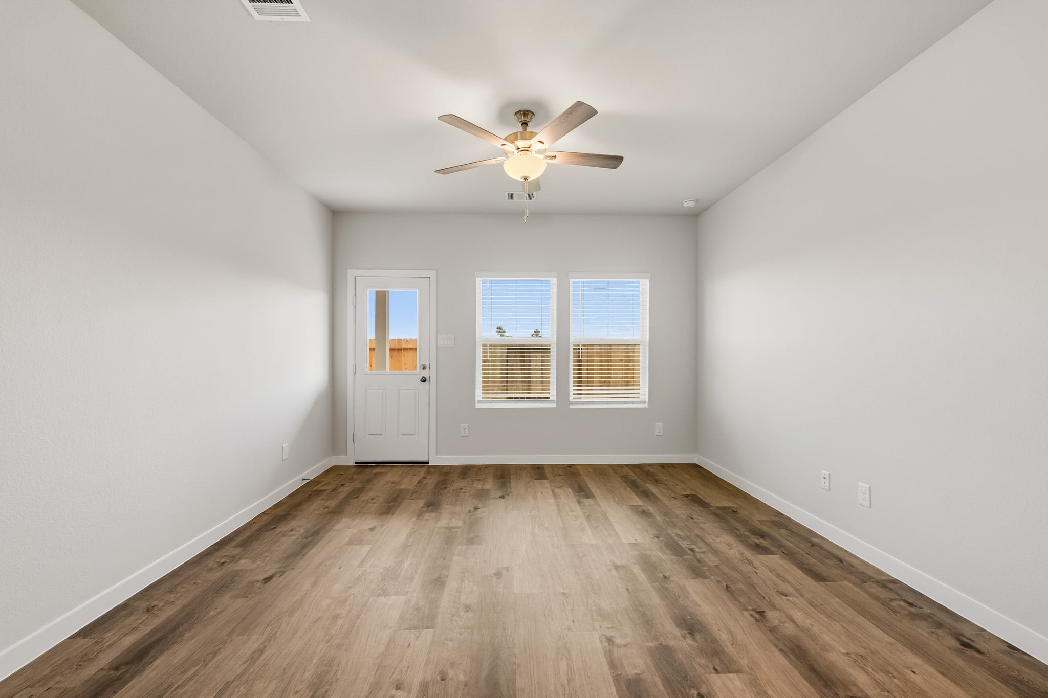 A room with a ceiling fan and a wood floor.