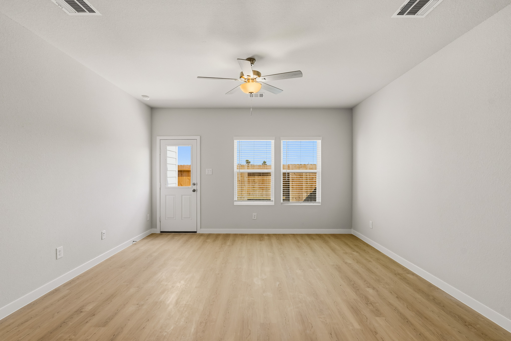 A room with a ceiling fan and a wood floor.