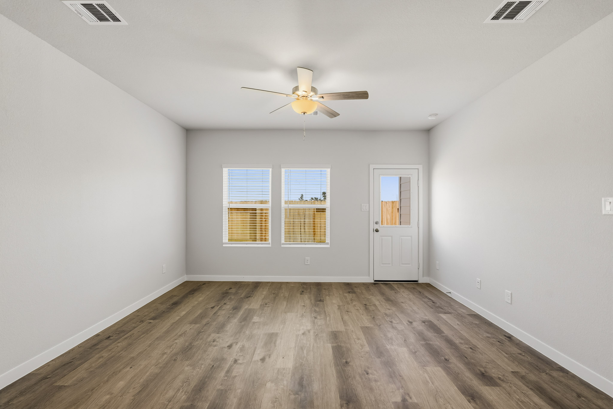 A room with a ceiling fan and a wood floor.