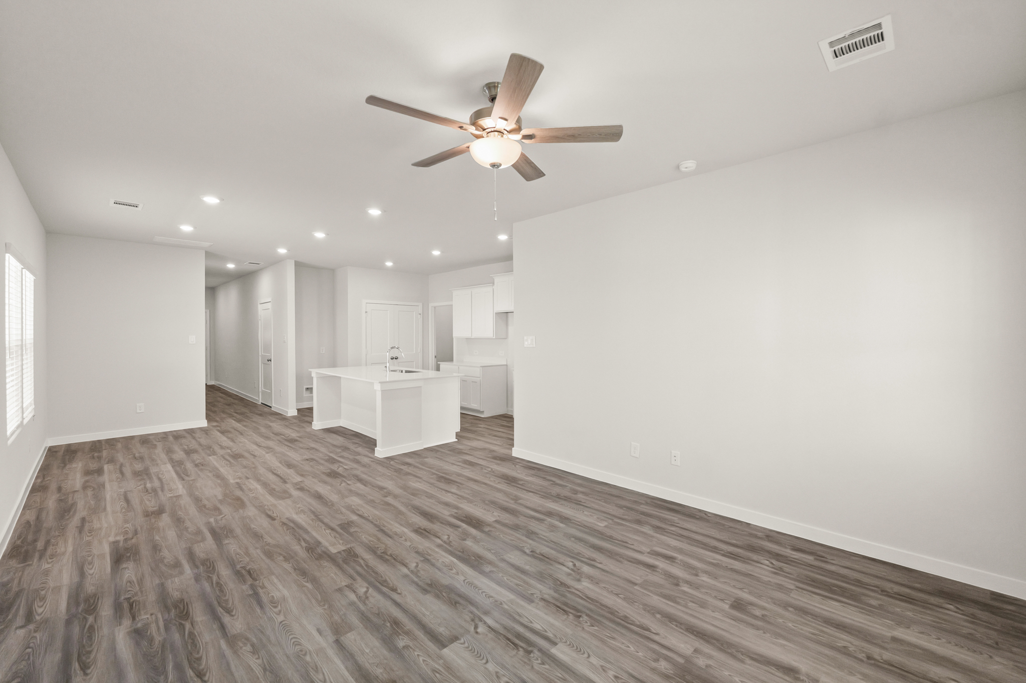 A large empty room with a ceiling fan and a table.