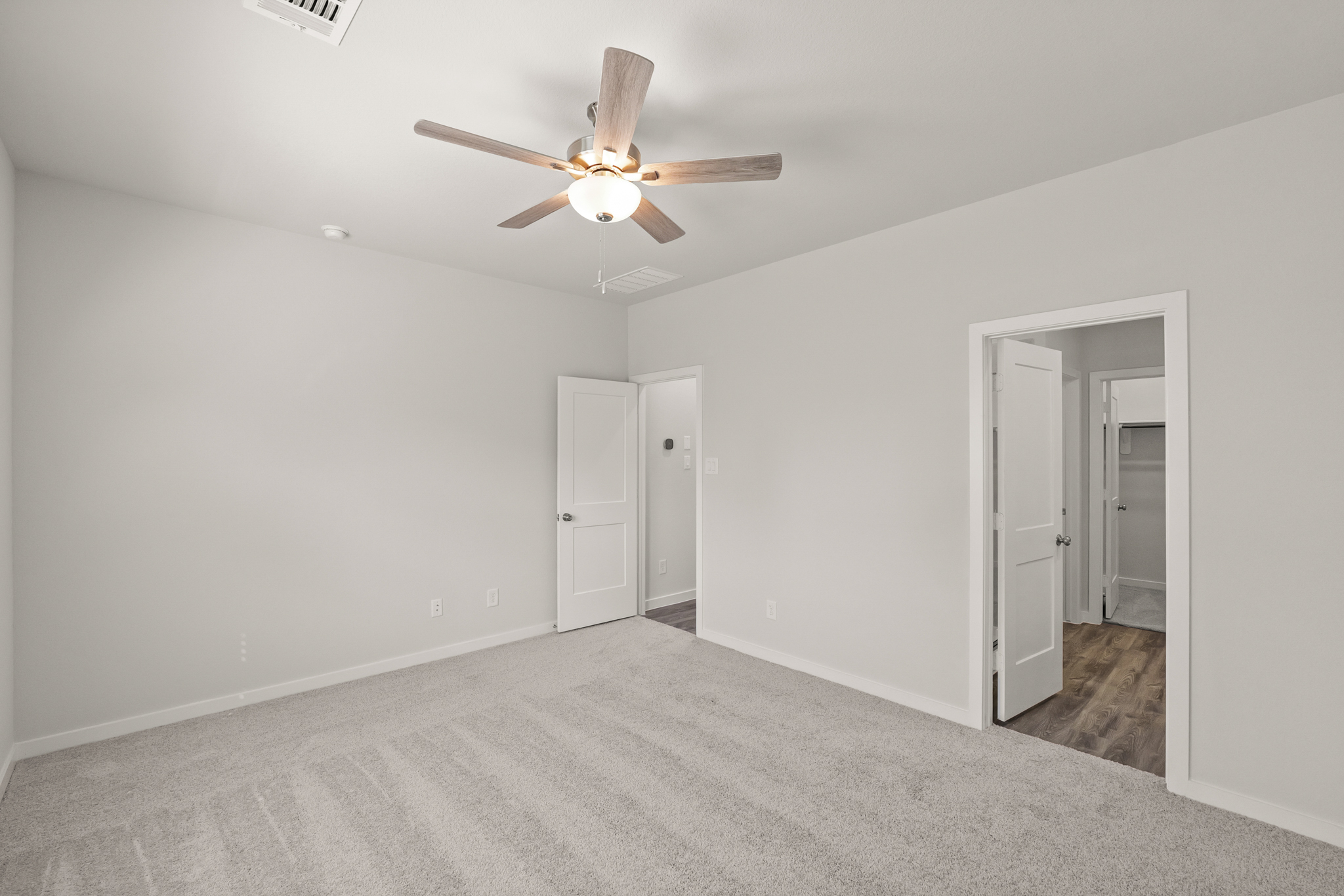 A room with a ceiling fan and a door.