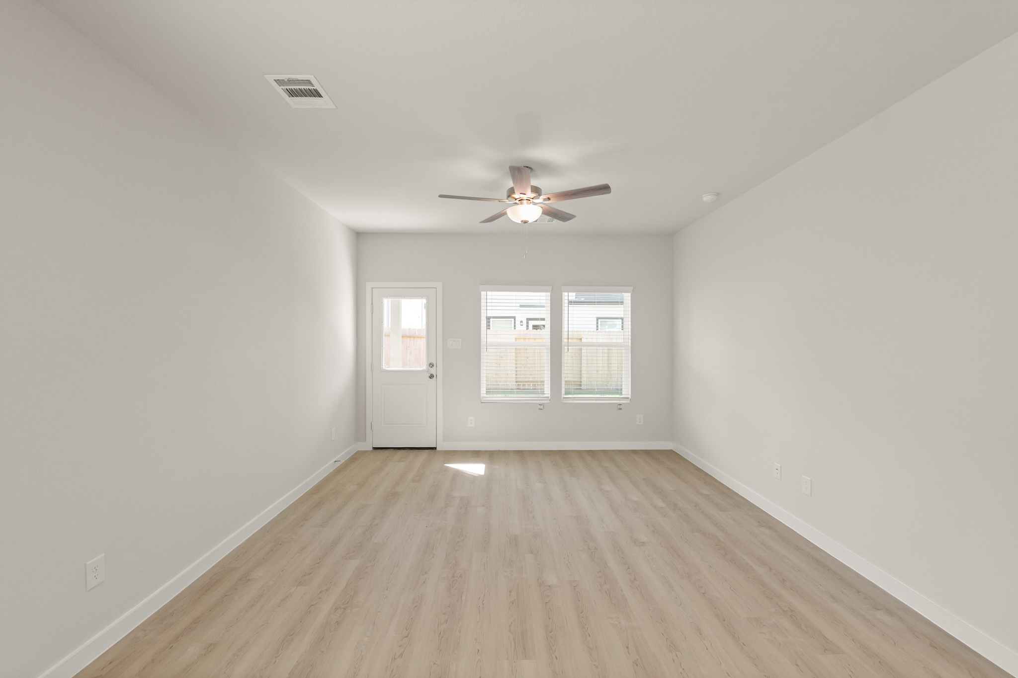 A room with a ceiling fan and a wood floor.