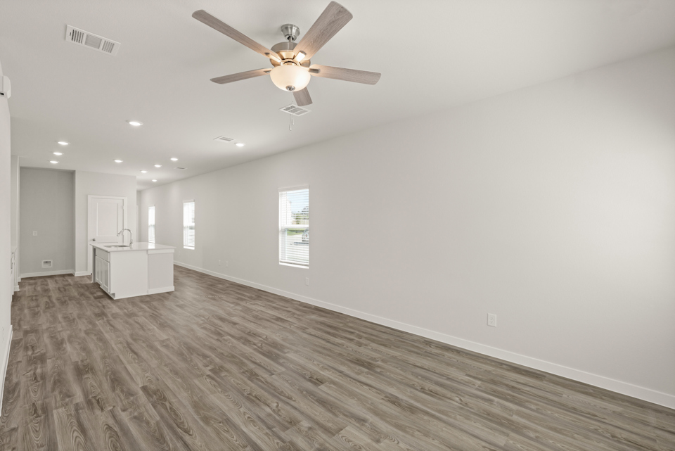 A room with a ceiling fan and a wood floor.