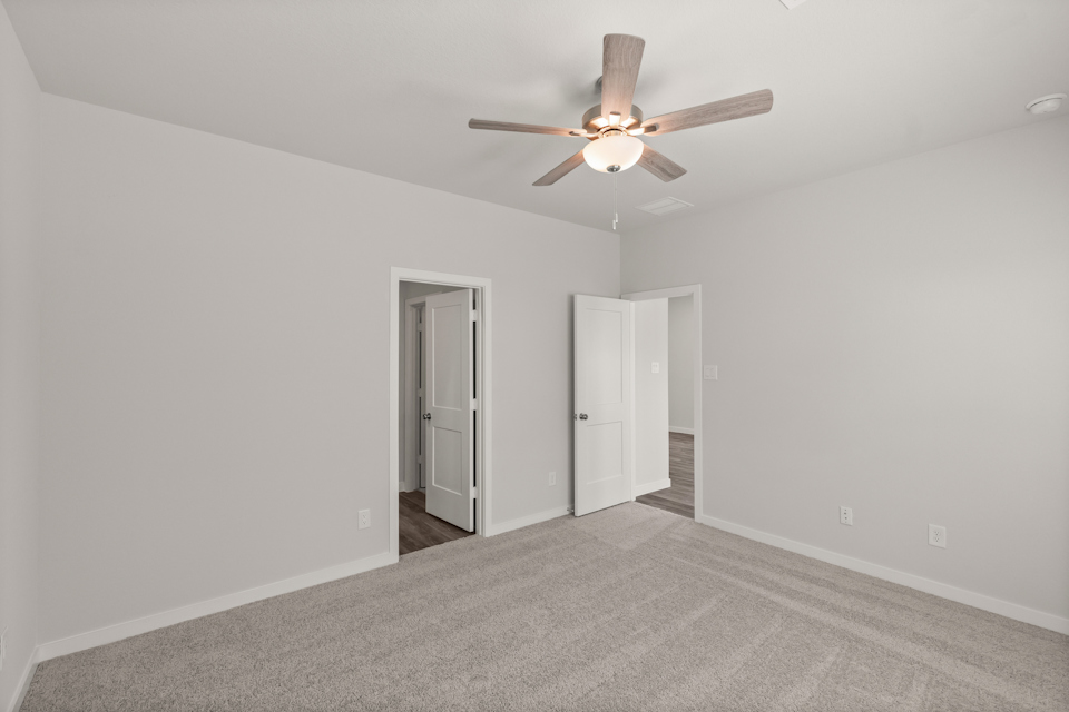 A room with a ceiling fan and a door.