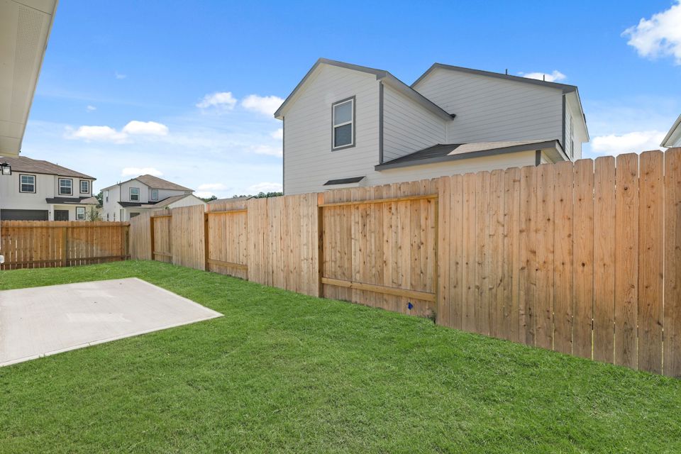 A fenced in yard with a house in the background.
