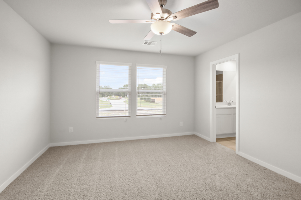 A large white room with a ceiling fan and a window.