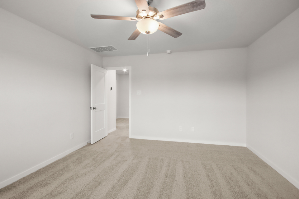 A room with a ceiling fan and a carpet.