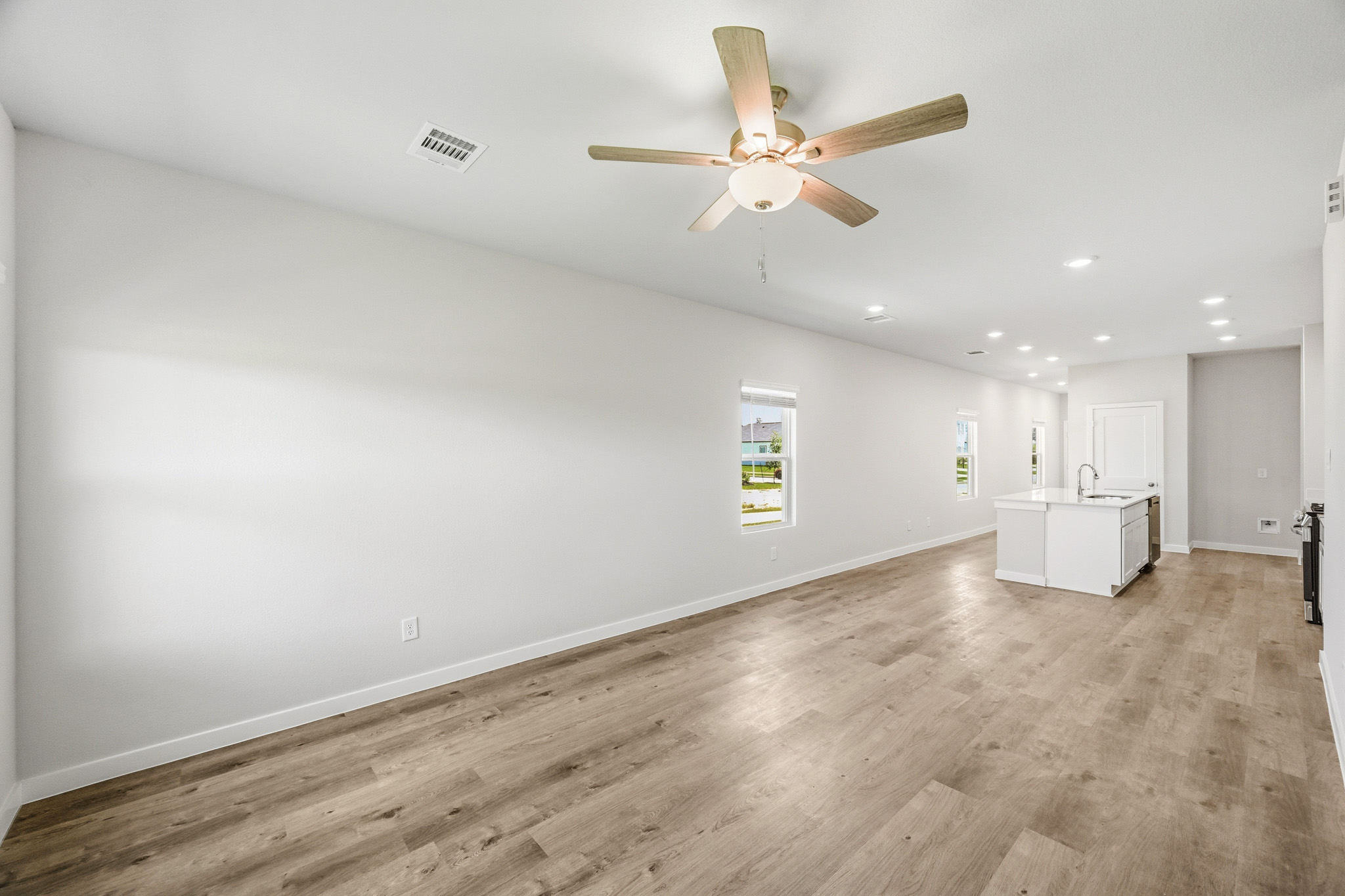 A room with a ceiling fan and wood floors.