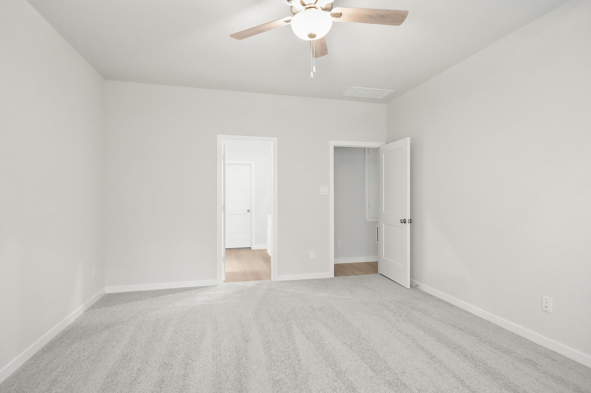 A room with a ceiling fan and a carpet.