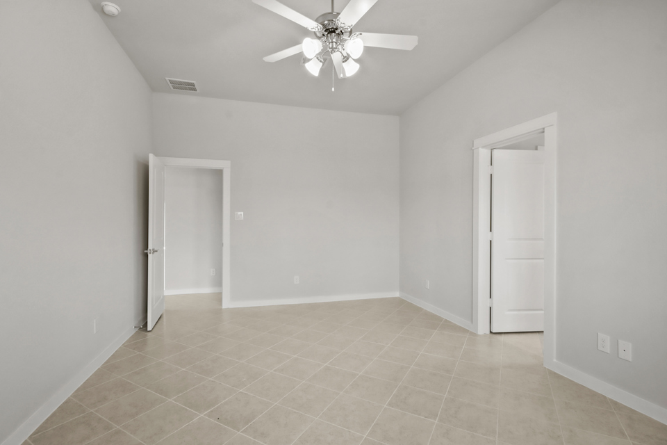 A room with a ceiling fan and a door.