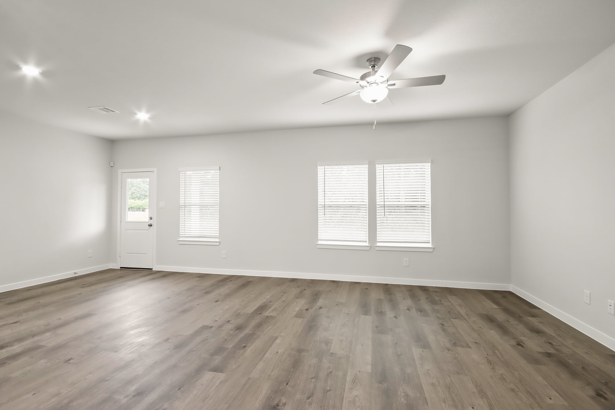 A room with a ceiling fan and a wood floor.