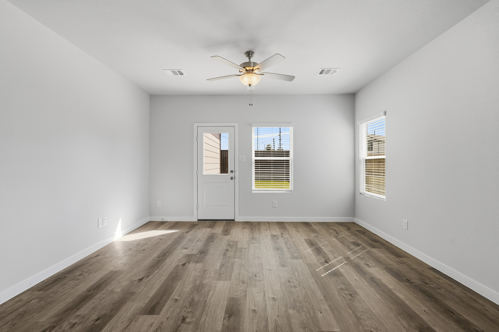 A room with a wood floor and a ceiling fan.