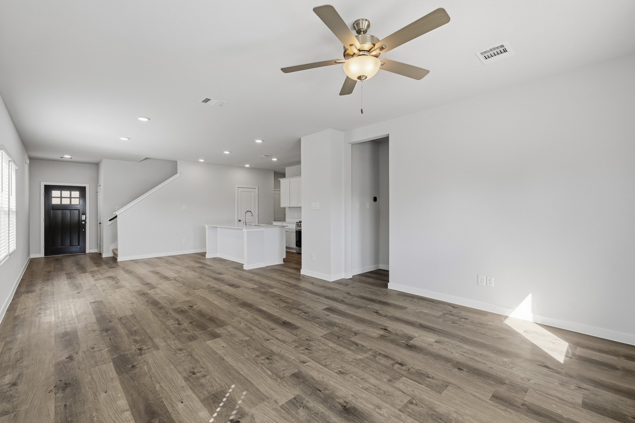 A large empty room with a ceiling fan and wood floors.