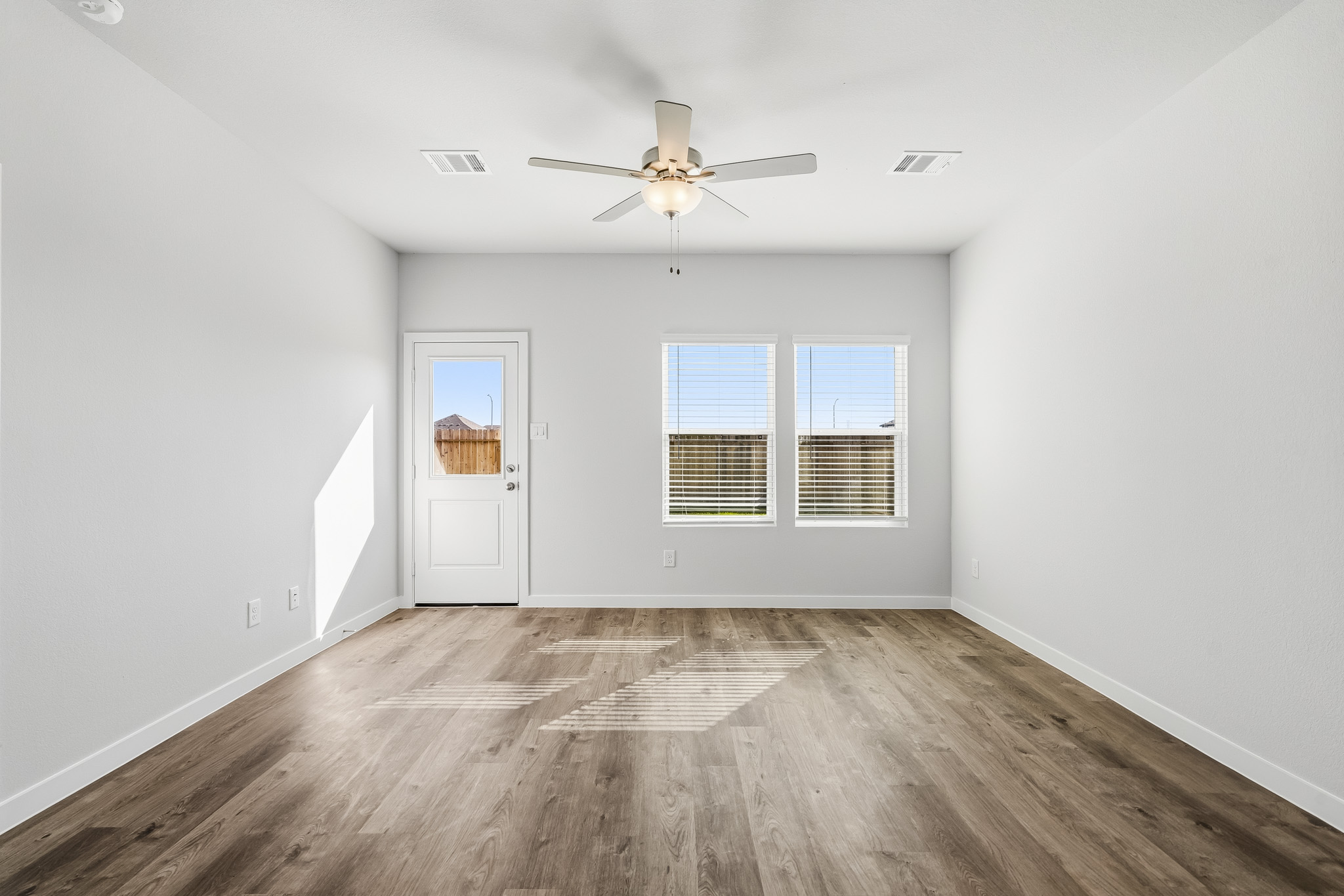 A room with a ceiling fan and a wood floor.
