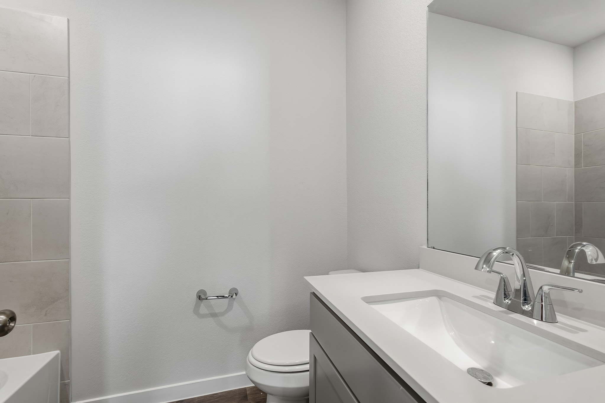 A bathroom with a sink toilet and mirror.