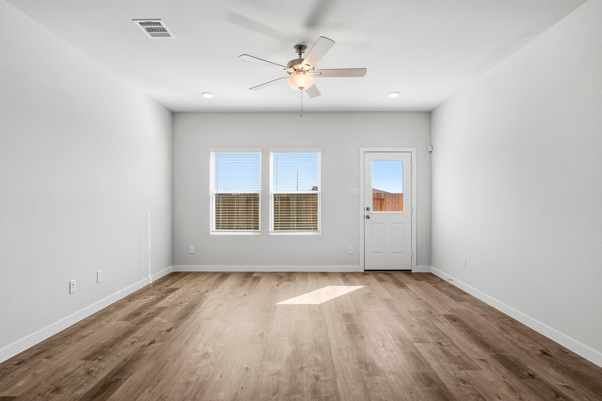 A room with a ceiling fan and a wood floor.