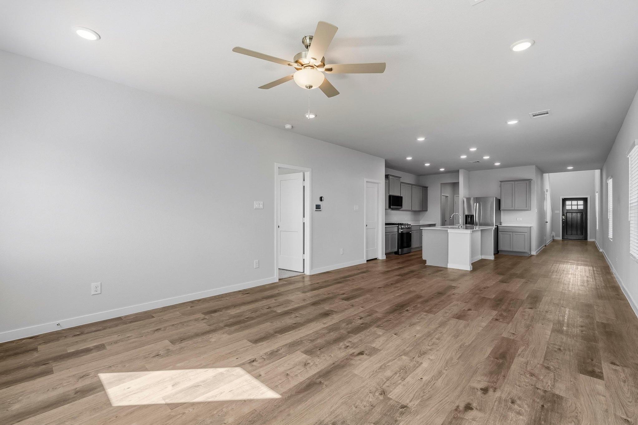 A large empty room with a wood floor and a ceiling fan.
