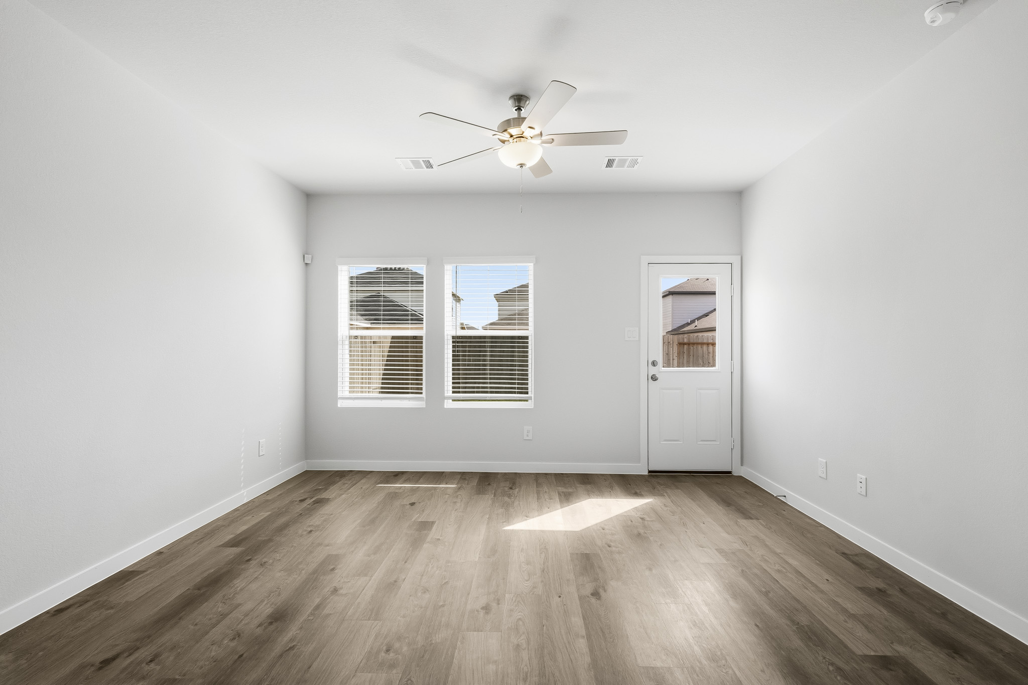 A room with a ceiling fan and a wood floor.