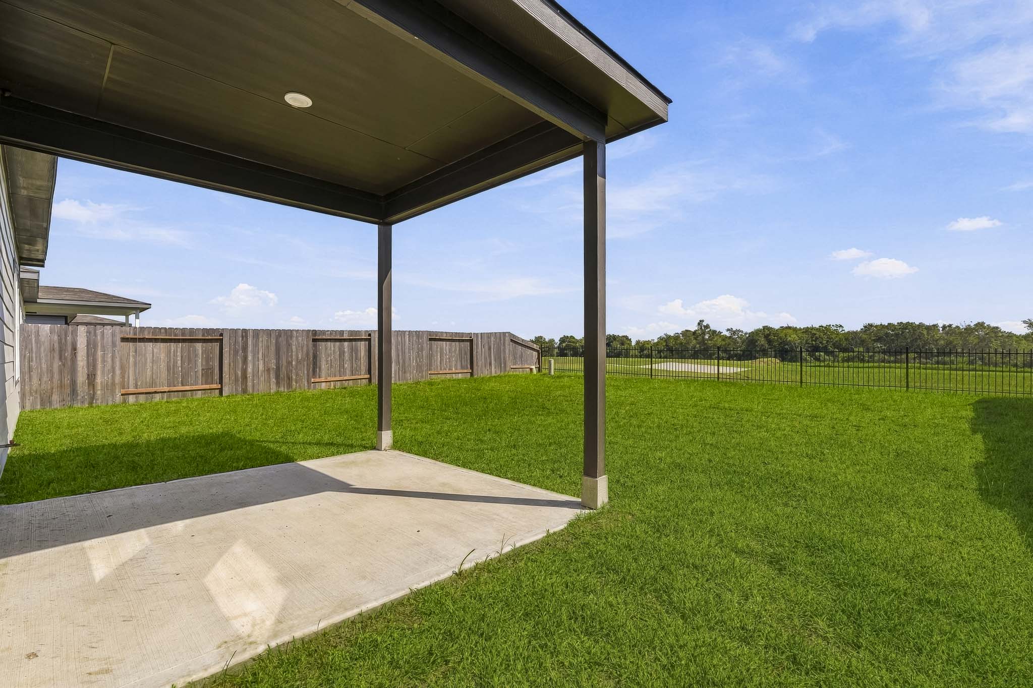 A backyard with a fence and a grass yard.
