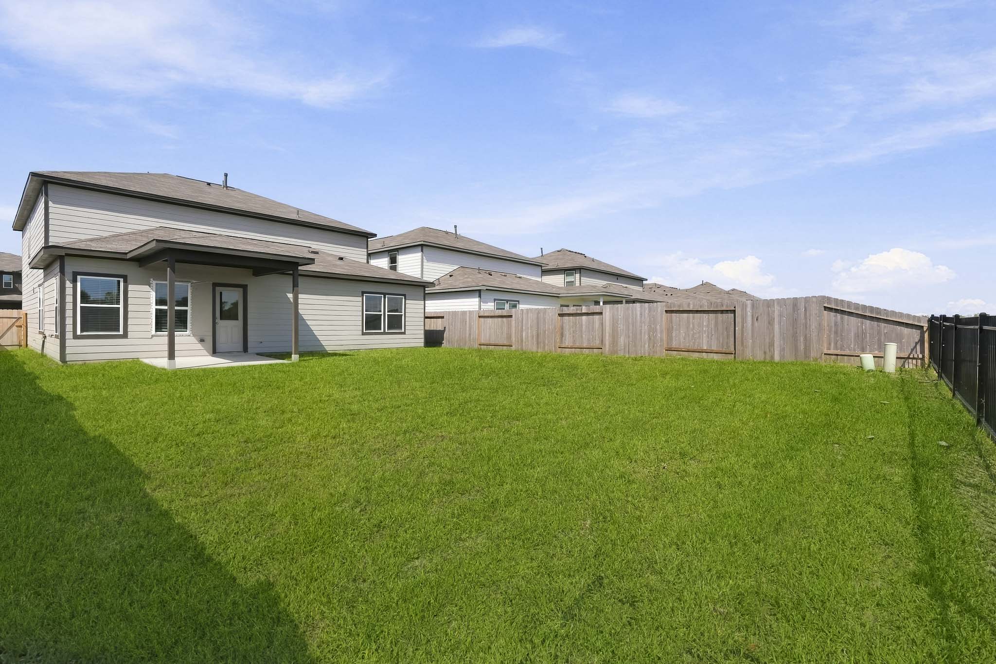 A fenced in yard with a house in the background.