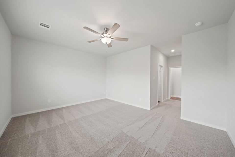 A room with a ceiling fan and a carpet.