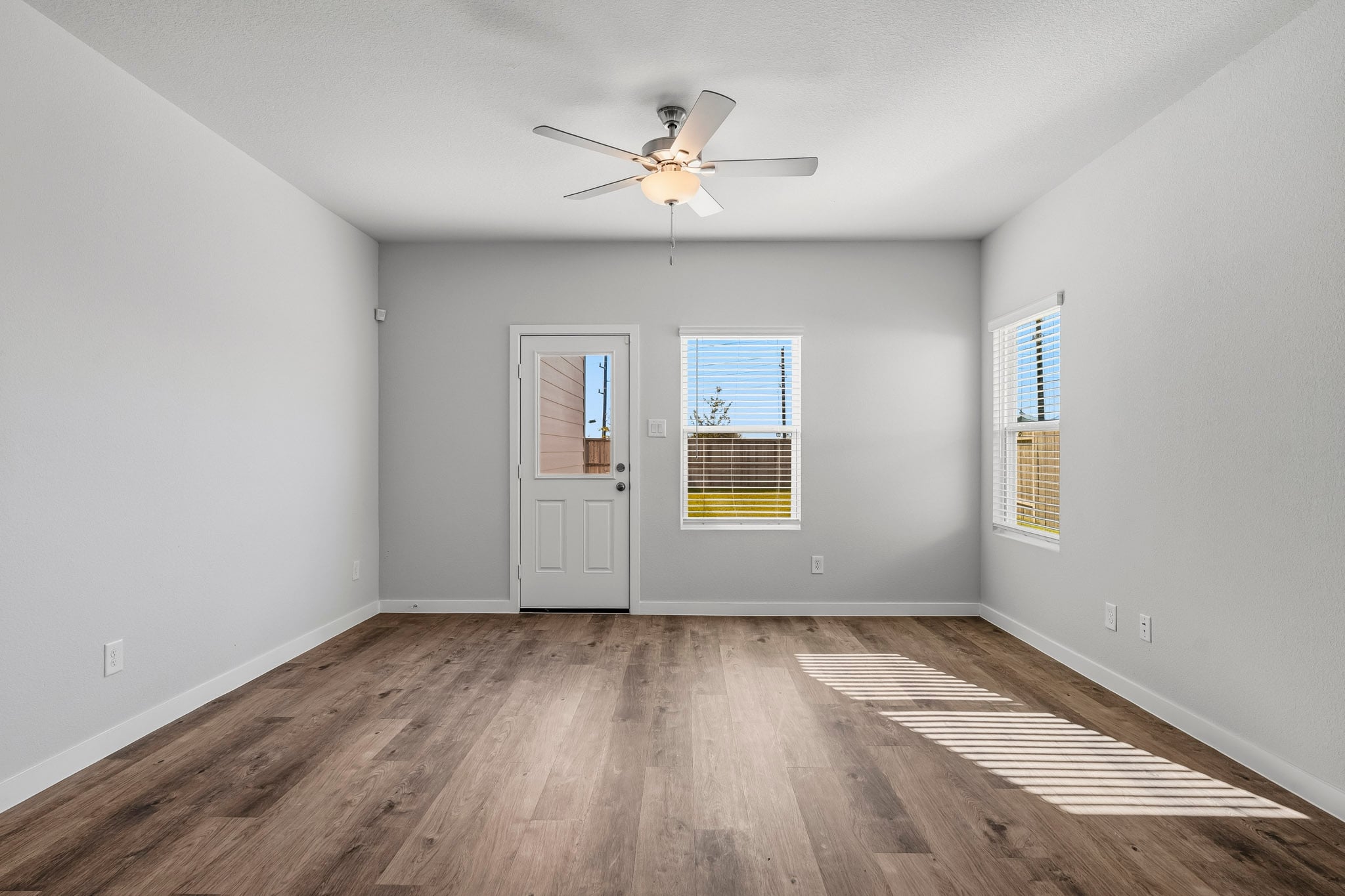 A room with a ceiling fan and a wood floor.