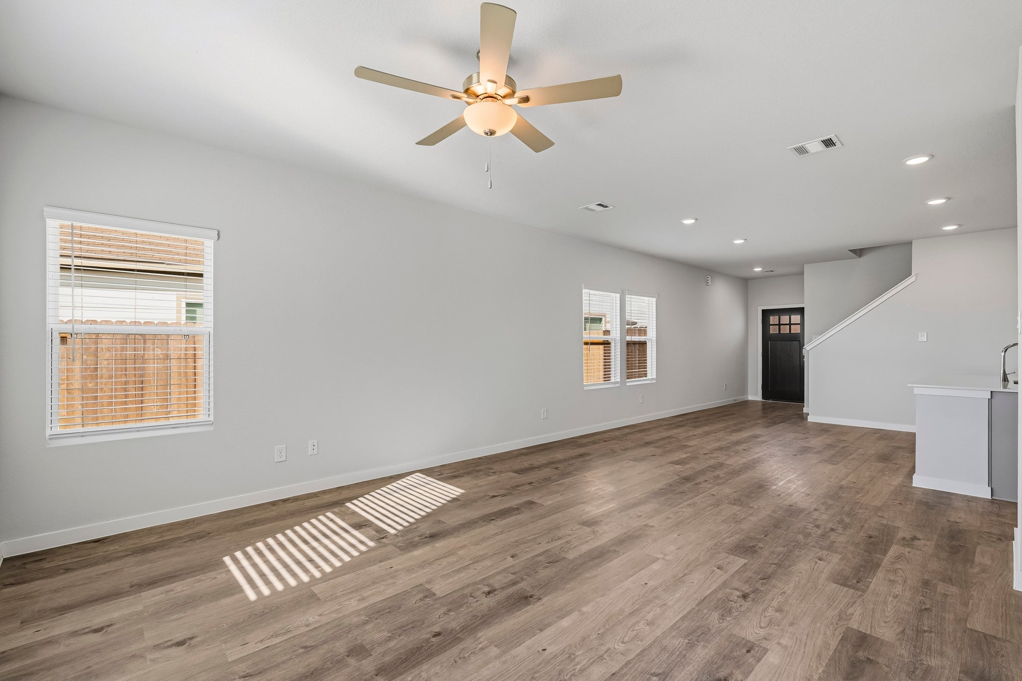 A room with a ceiling fan and wood floor.