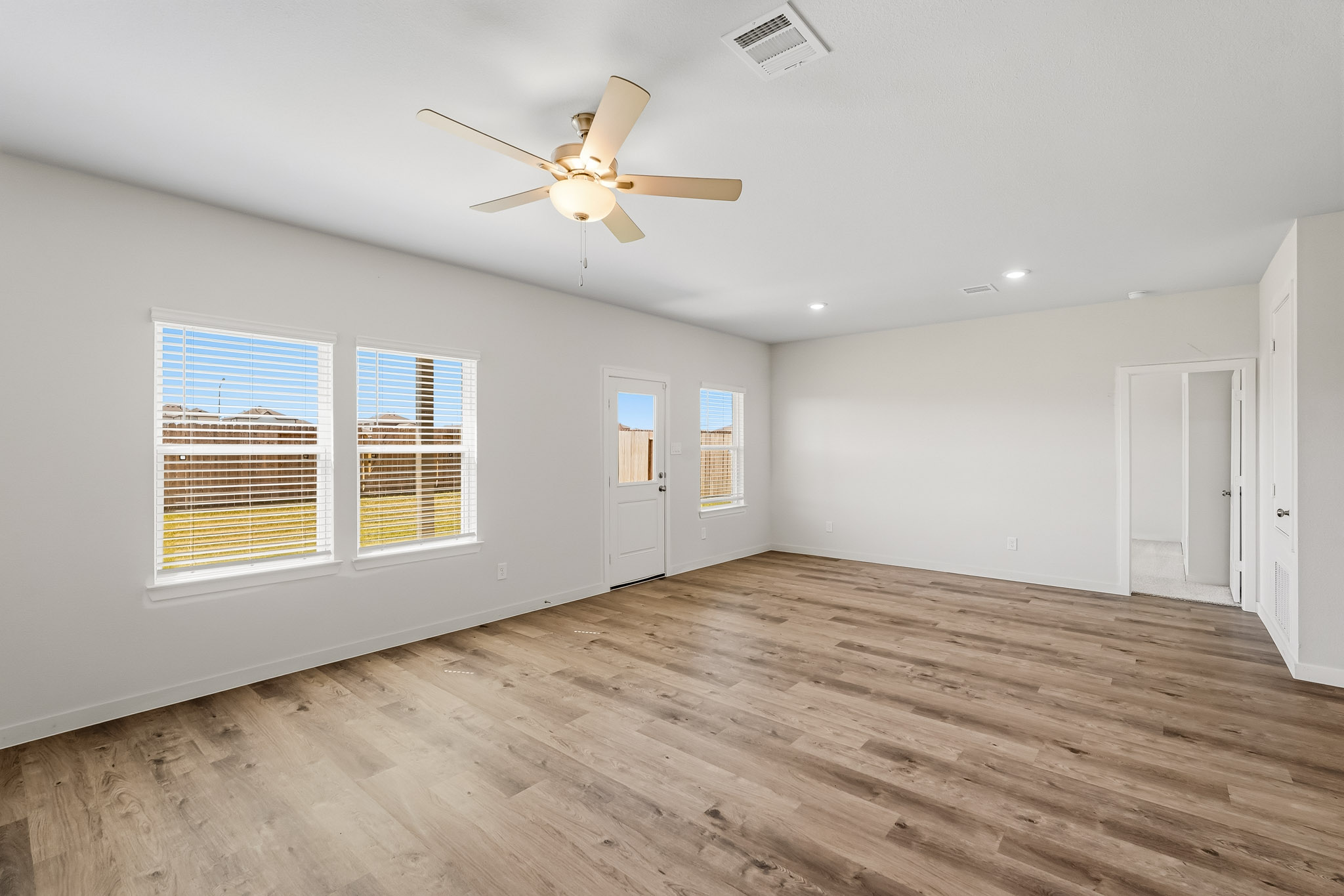 A room with a ceiling fan and a wood floor.