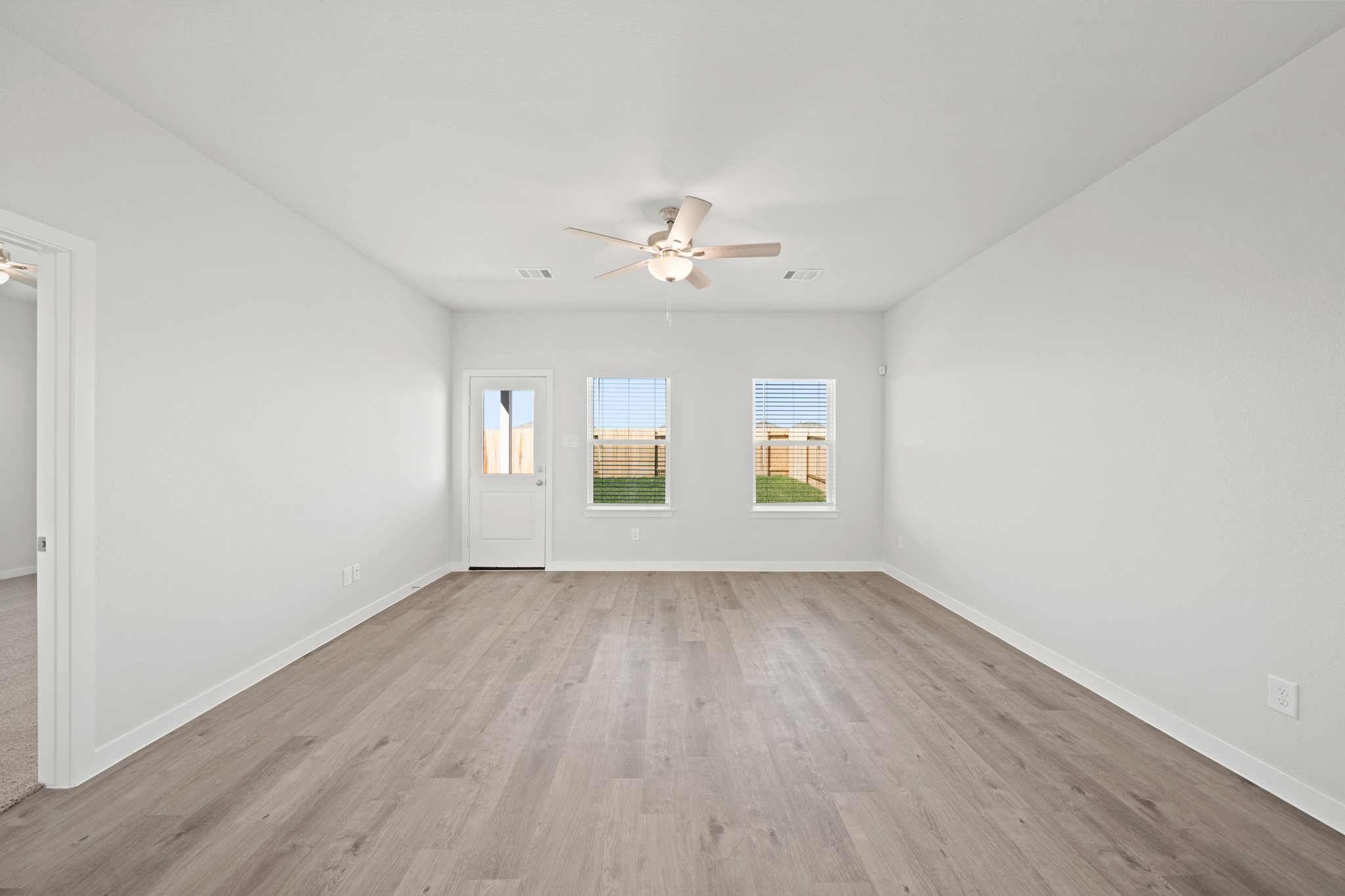 A room with a ceiling fan and a wood floor.