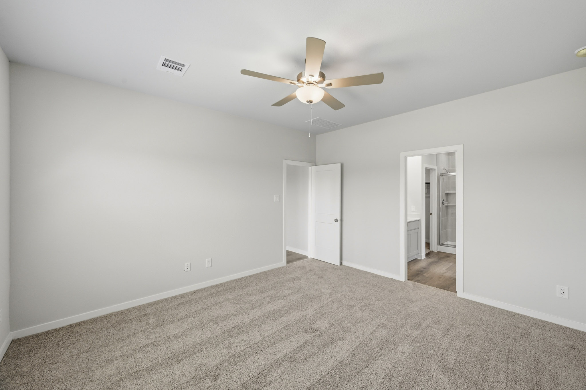 A room with a ceiling fan and a carpet.