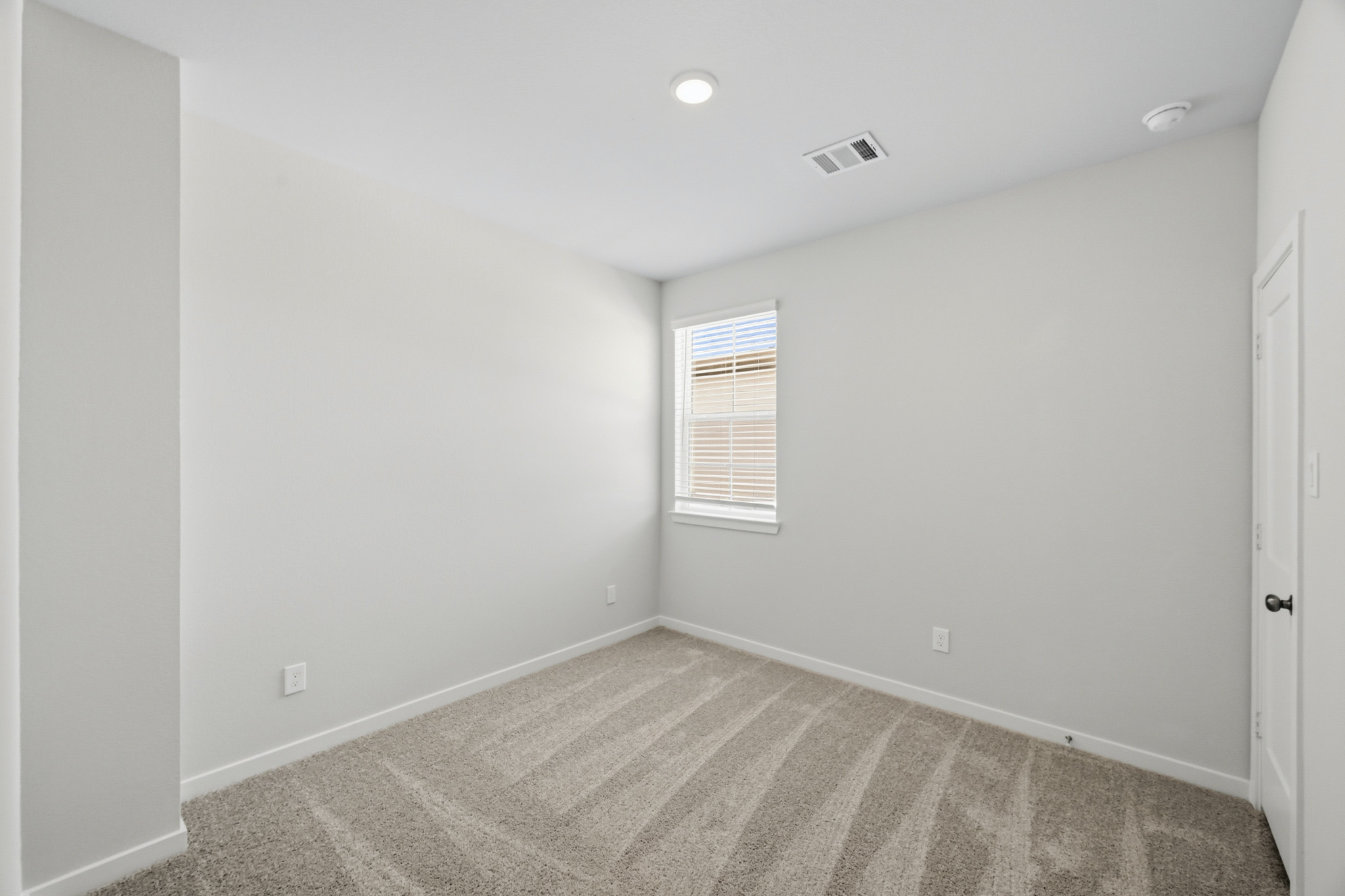 A room with a carpet and a window.