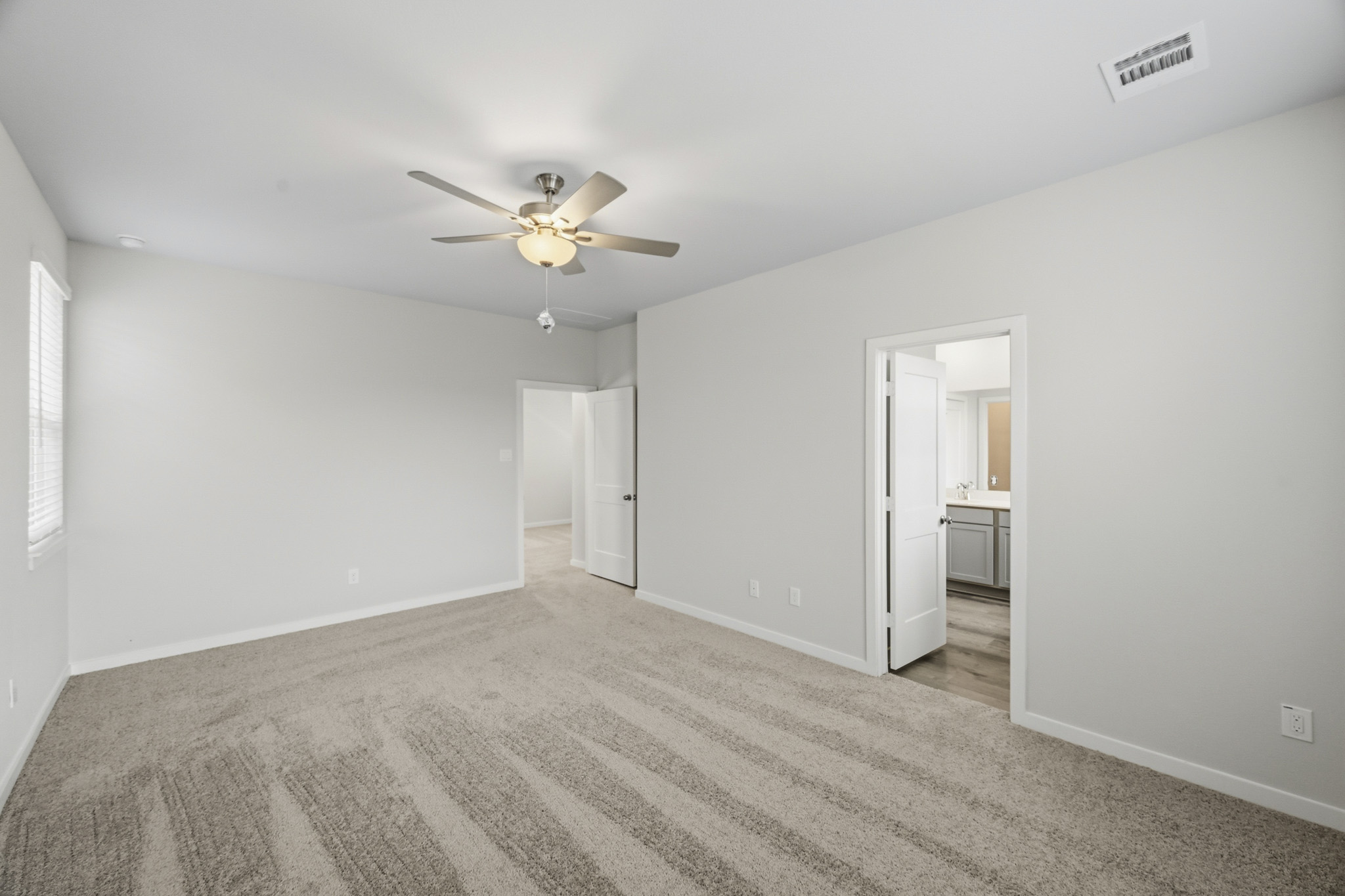 A room with a ceiling fan and a door.
