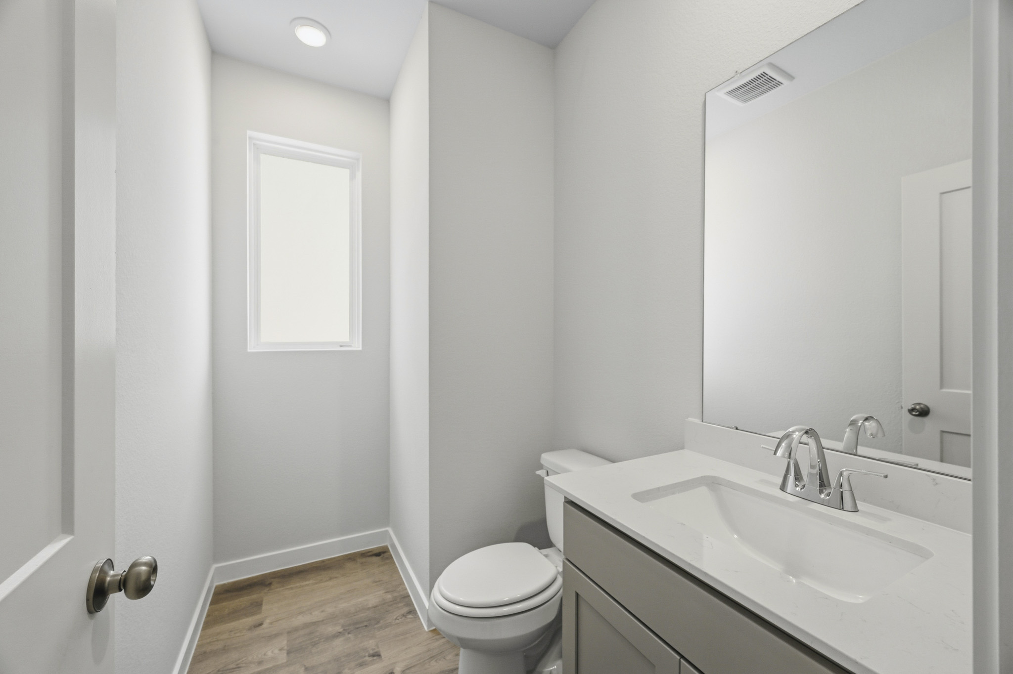 A bathroom with a sink toilet and mirror.