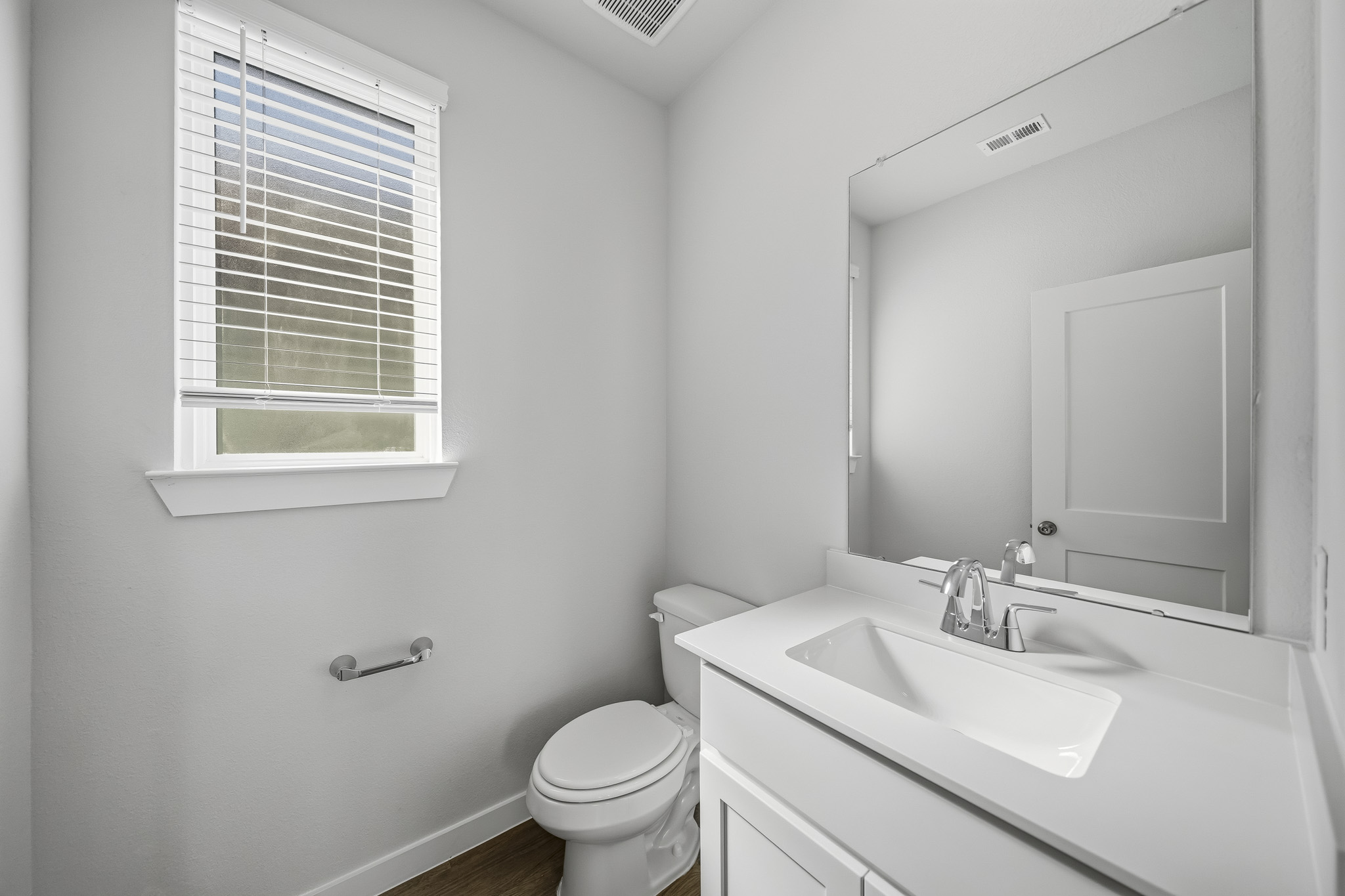 A bathroom with a sink toilet and a mirror.